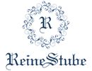 Blaues Ornament mit "R" und Text "ReineStube" darunter in stilisierter Schrift.