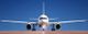 Flugzeug auf Landebahn mit blauem Himmel im Hintergrund, frontal fotografiert.