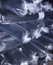 Pilas de láminas metálicas cubiertas con plástico transparente, apiladas en un almacén oscuro.