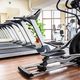 Modern gym with treadmills, exercise bikes, and elliptical machines on a wooden floor.