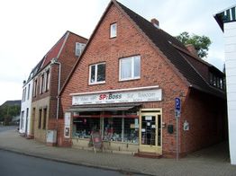 Rotes Backsteingebäude an einer Straßenecke mit Elektronikgeschäft im Erdgeschoss.