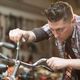 Person focusing intensely while fixing a bicycle handlebar with a screwdriver.