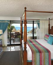 Habitación con cama de dosel, decoración colorida y balcón con vista al mar.