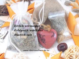 Kräutersäckchen und Deko auf weißem Hintergrund, daneben ein rotes Herz mit Ornamenten.