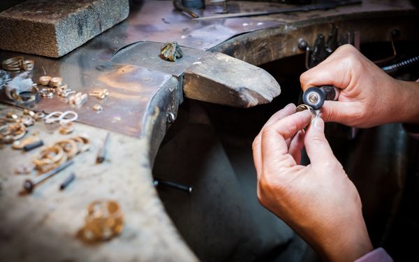Ein Juwelier poliert einen umgearbeiteten Ring in seinem Atelier. 