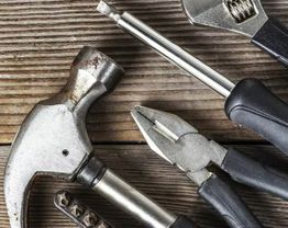 Ferramentas em uma mesa de madeira, incluindo martelo, chave de fenda, alicate e chave inglesa.