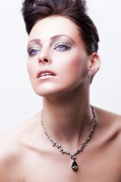 Eine Frau mit Hochsteckfrisur und Halskette, im Profil nach oben blickend.