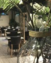 Vase mit weißen Blumen in einem stilvollen Restaurant mit Holztischen und Stühlen im Hintergrund.