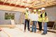 Construction workers in helmets review blueprints inside a building under construction.