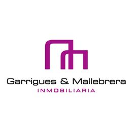 Logo de Garrigues & Mallebrera Inmobiliaria, con letras moradas y un diseño geométrico.