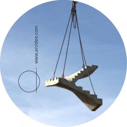 Ein Betonteil in Form einer Treppe wird mit Ketten in den Himmel gehoben.