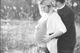 Pregnant woman embraced by partner in a peaceful field setting.