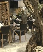 Gemütliches Restaurant mit Holzmöbeln und verwittertem Baumstamm als Dekoration.