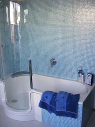 Modernes Badezimmer mit blauen Fliesen, Dusche, Badewanne und blauen Handtüchern.