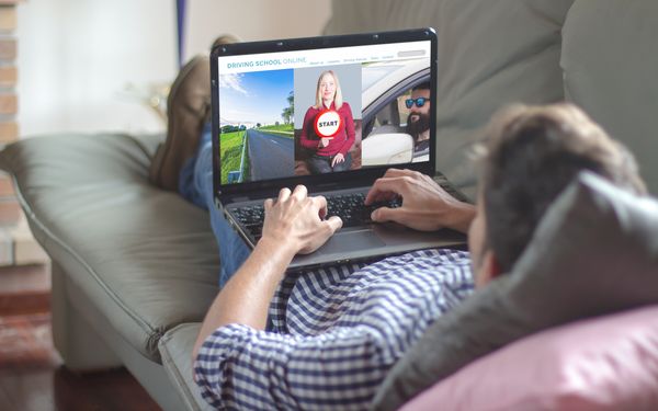 Ein Fahrschüler lernt für seinen Führerschein online auf einen Laptop, für seine Theorieprüfung. 