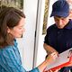 Woman signing a clipboard held by a delivery person at a door.