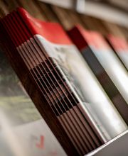 Zeitschriften in einem Regal, teilweise unscharf, mit rotem und weißem Coverdesign.