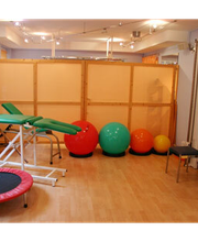 Fitnessraum mit Gymnastikbällen, Trampolin, Behandlungsbank und Fitnessgerät.