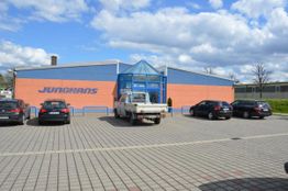 Parkplatz mit fünf Autos vor einem Backsteingebäude mit blauem Eingang und dem Schriftzug "JUNCHANS".