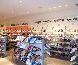 Schuhgeschäft mit Regalen voller Schuhe und Markenlogos an den Wänden.