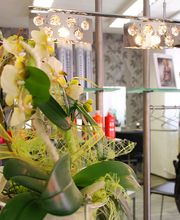 Blumengesteck im Friseursalon, im Hintergrund Kleiderständer und dekorative Beleuchtung.