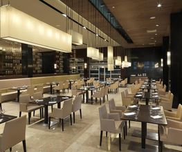 Restaurante moderno con mesas y sillas elegantes, iluminación suave y ambiente acogedor.