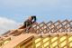 Worker installing wooden roof trusses on a house.