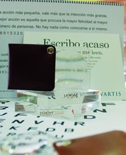 Lupa sobre texto, calendario y notas de fondo en una mesa; resaltado: "Escribo acaso, me leen".