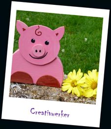 Holzschwein und gelbe Blumen auf Gras. Text: "Creatiwerker".