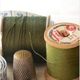 Spools of green thread, a thimble, and tape measure on a sewing table.