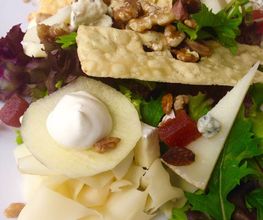 Ensalada con lechuga, manzana, frutos secos, queso y trozos de pan crujiente.