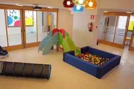 Sala de juegos colorida con tobogán, piscina de pelotas y túnel plástico.
