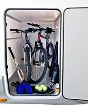 Bicicletas, raquetas y pelotas de tenis almacenadas en el compartimento trasero de una caravana.