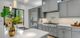 Modern kitchen with grey cabinets, stainless steel appliances, and white countertops.