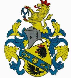 Wappen mit Löwen, Helm und blauer Banderole mit Blumenmotiven auf gelbem Schild.