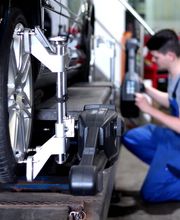 Automechaniker arbeitet an einem Auto, das auf einer Hebebühne steht.