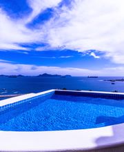 Piscina infinita con vista al mar y cielo parcialmente nublado.