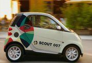 Kleines Auto mit bunter Grafik und "SCOUT 007"-Schriftzug auf der Seite, fährt schnell vorbei.