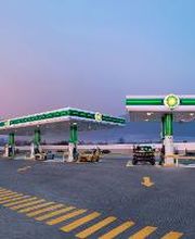 Gasolinera vacía al atardecer, con dos coches y señales de tráfico en el suelo.