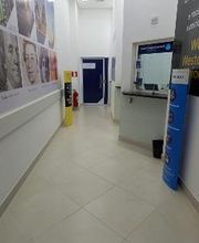 Corredor de banco com guichê de atendimento e pôsteres de rostos nas paredes.