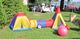 Bunte Kinderspielzelte und -spielzeug auf einer Wiese, im Hintergrund Menschen beim Essen.