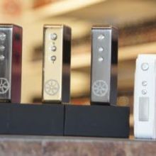 Four electronic devices on display, three metallic and one white, each on a black base.