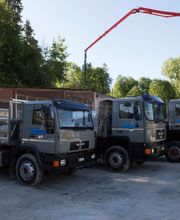 Drei graue Lkws stehen nebeneinander auf einem Parkplatz mit grünem Hintergrund und Kranarm.
