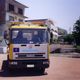 Camion giallo con logo Europ Assistance parcheggiato su strada, edificio sullo sfondo.