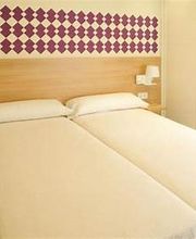 Habitación con dos camas individuales, cabecero de madera y pared decorada con rombos púrpuras.