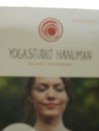 Unschärfer Flyer für "Yogastudio Hanuman" mit einer meditierenden Frau im Hintergrund.