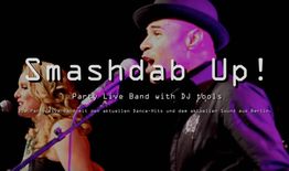 Zwei Musiker auf der Bühne mit Mikrofonen, Schriftzug "Smashdab Up!" im Vordergrund.