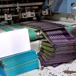 Stacks of colorful printed paper exiting a printing machine.