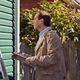 Man inspecting house exterior with a clipboard in hand, standing near green siding and a fence.