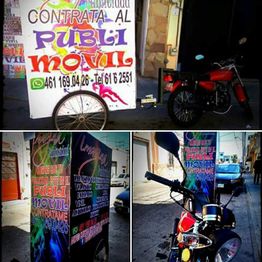 Motocicleta con carteles coloridos anunciando "Publi Móvil" en una calle urbana.